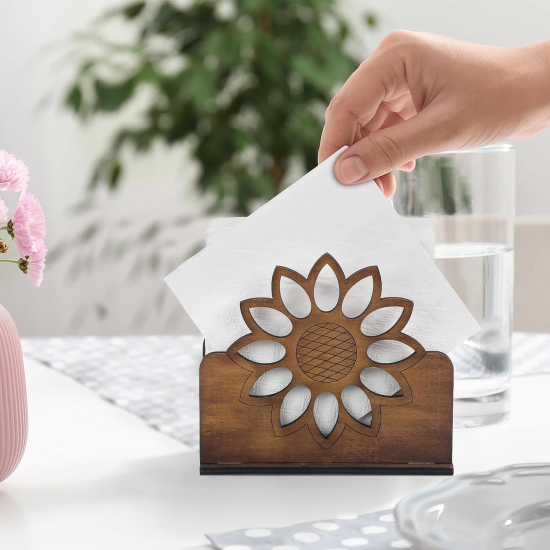 Hand taking a napkin from the wooden sunflower napkin holder